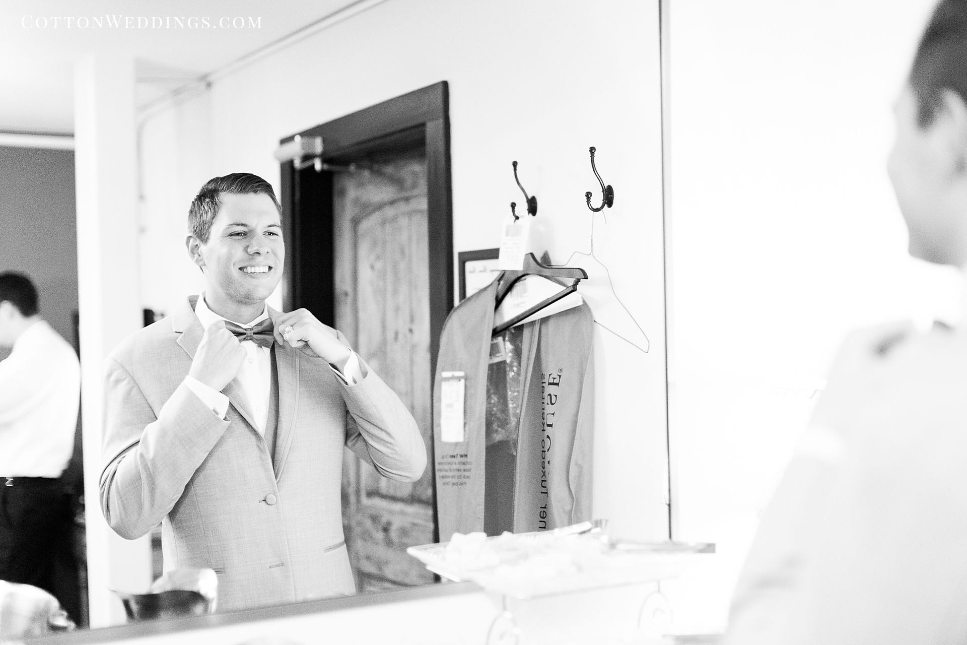 groom adjusting bowtie in mirror