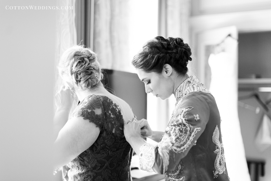 bride helping mother into dress