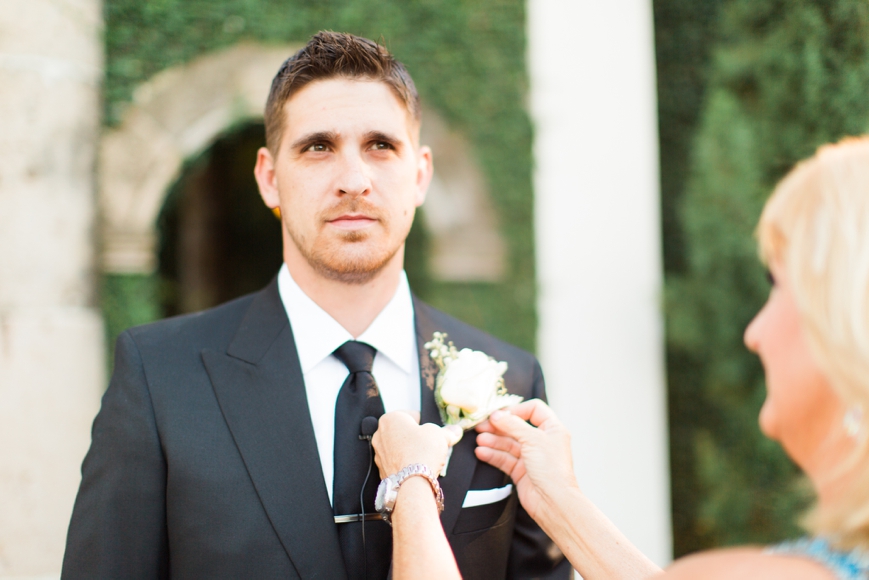 mom putting boutonniere on groom 