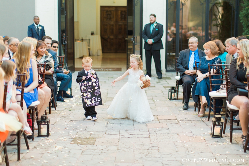 cute ring bearer and flower girl walking down the aisle with sign