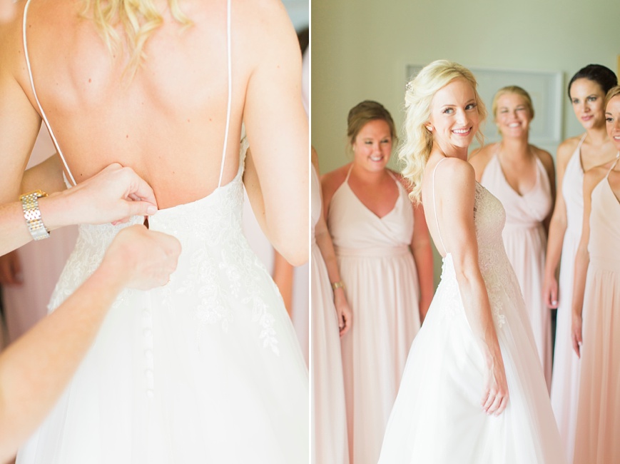 bride putting on dress with bridesmaids