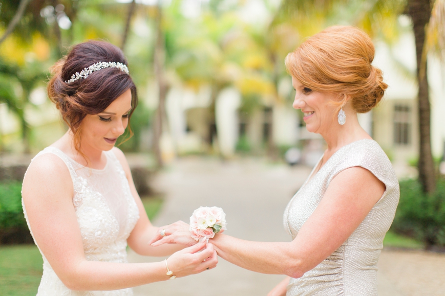 bride putting corsage on mom