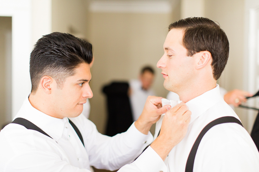 groomsman helping groom with bowtie