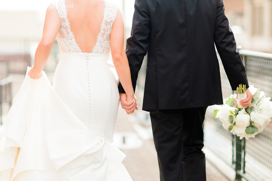 detail of bride and groom holding hands and walking away