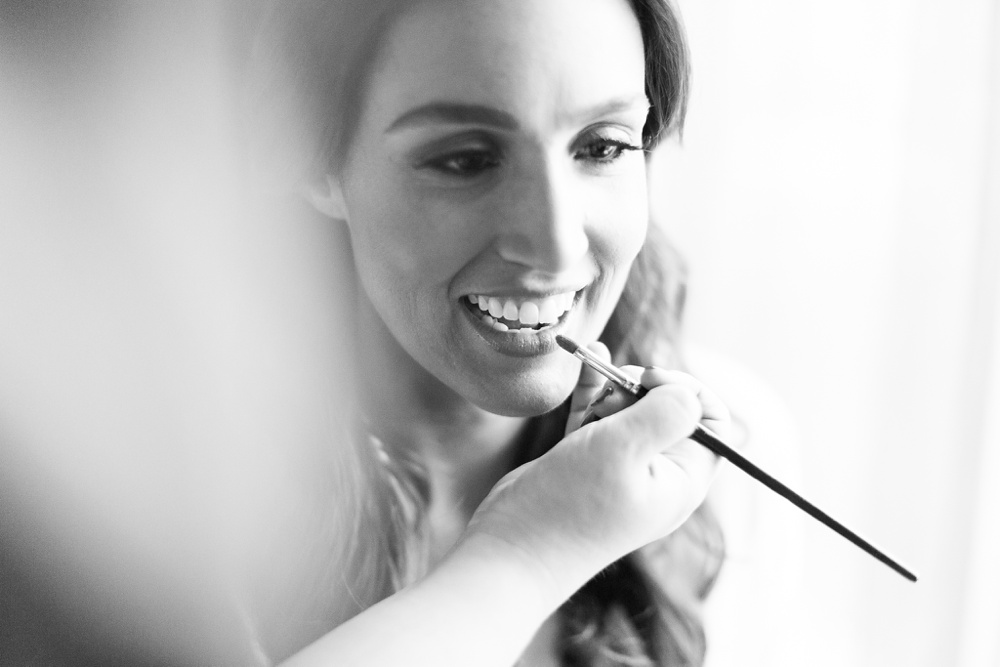 black and white portrait of bride putting on makeup